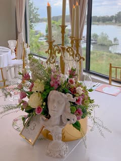 Floralna kompozicija sa zlatnim svećnjakom pored jezera